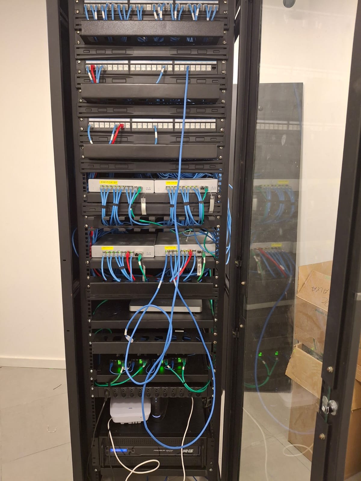 Rack de rede com patch panels, switches e cabos organizados